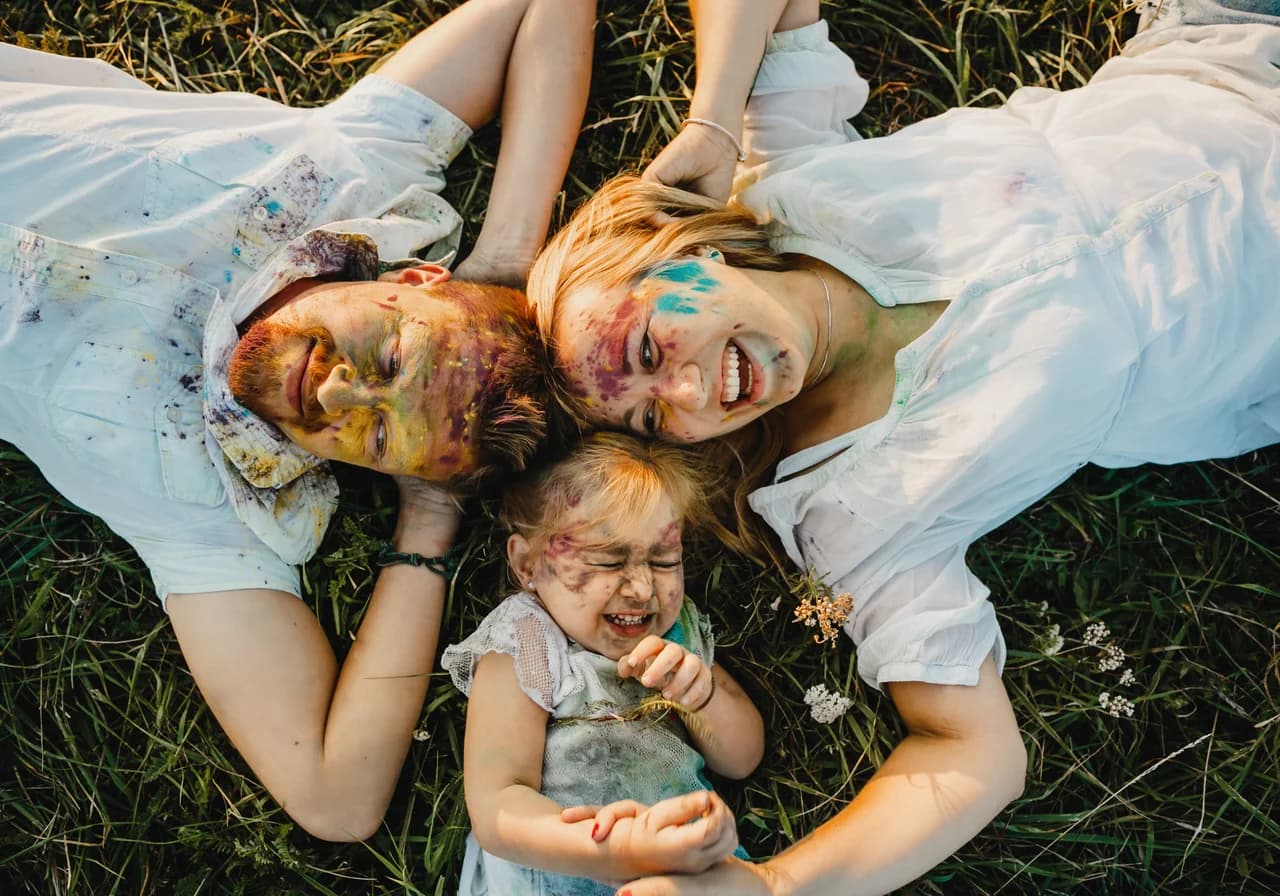 Glückliche Familie mit Kind liegt lachend auf einer Wiese