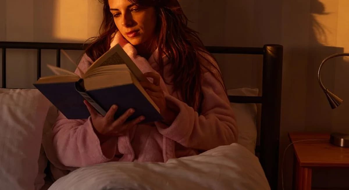 Frau liest ein Buch im Bett bei warmem Abendlicht